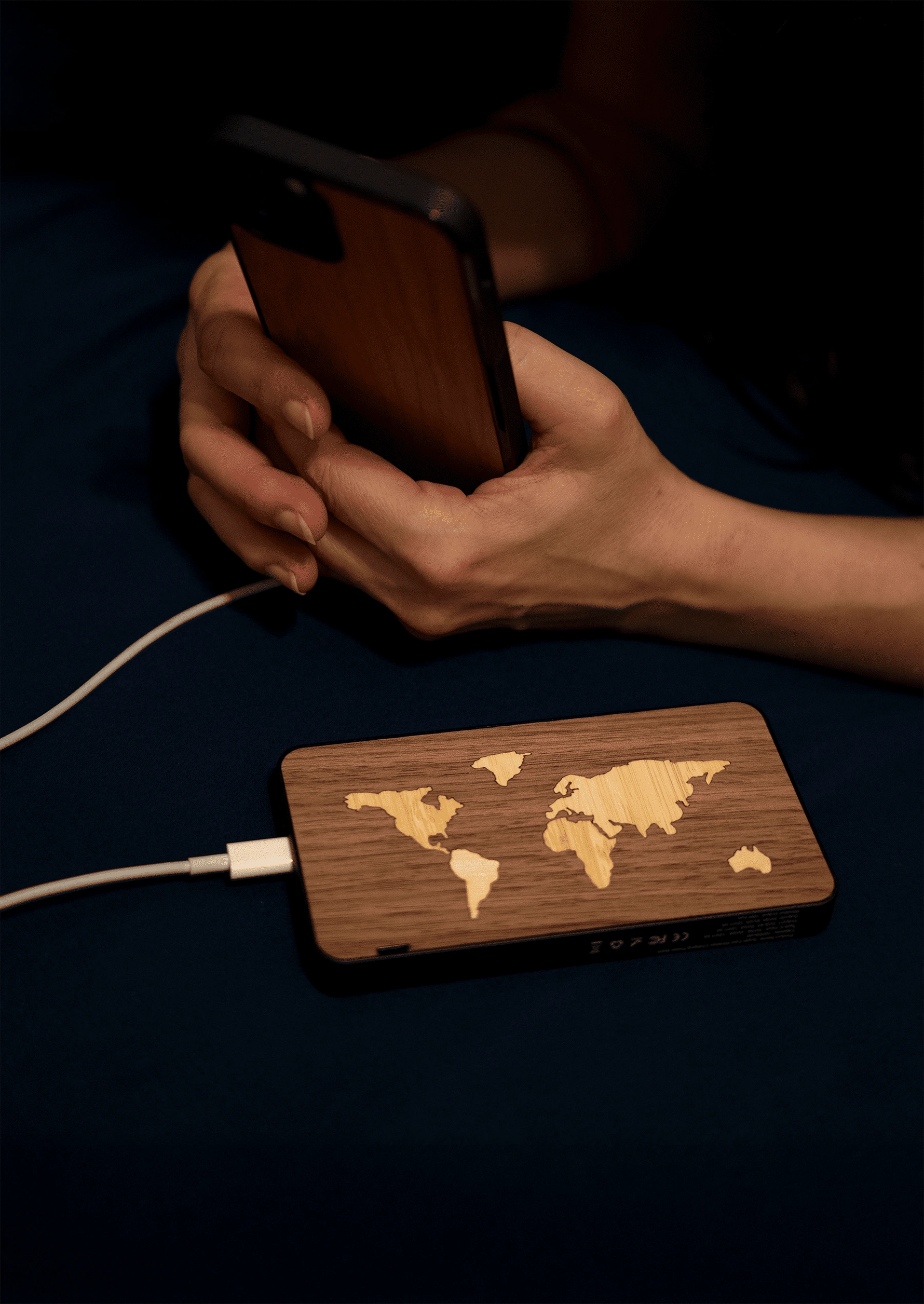 Batterie externe en bois modèle La Mappemonde d'une capacité.de 10 000 mAh reliée à un iPhone avec une coque en bois modèle Le Bois artisanale et Made in France