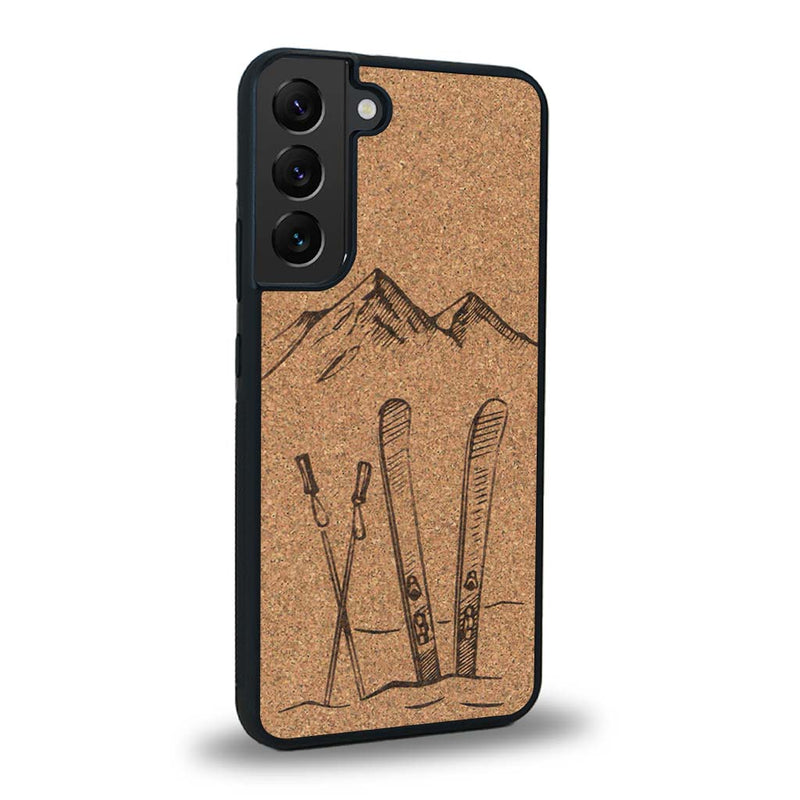 Coque de protection en bois véritable fabriquée en France pour Samsung S24 sur le thème de la montagne, du ski et de la neige avec un motif représentant une paire de ski plantée dans la neige avec en fond des montagnes enneigées