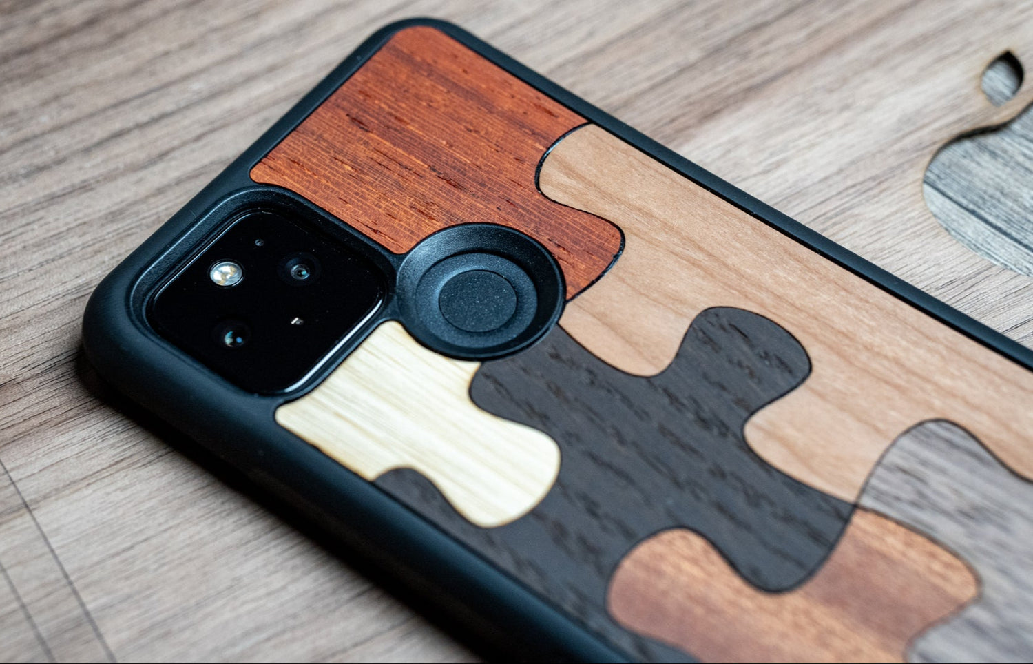 Un téléphone sur un bureau avec une coque en bois, modèle Puzzle.