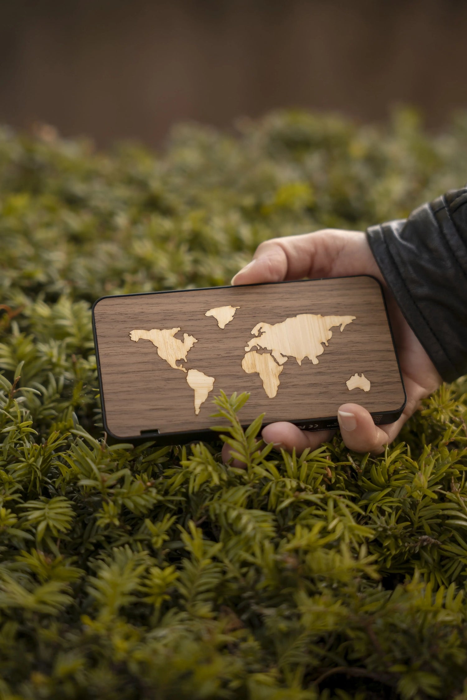 Main qui tient une batterie externe d'une capacité de charge pour téléphone de 10 000 mAh, modèle Le Mappemonde, artisanale et fabriquée en France à partir de bois véritable.