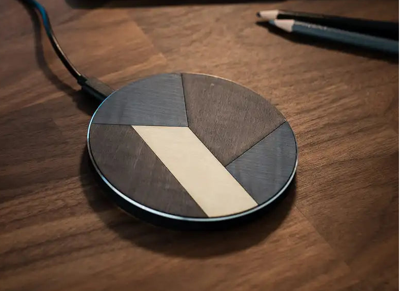 Chargeur à induction en bois sur un bureau, constitué de manière artisanale en France, par l'assemblage de différentes essences de bois, modèle L'Eclat Bleu.