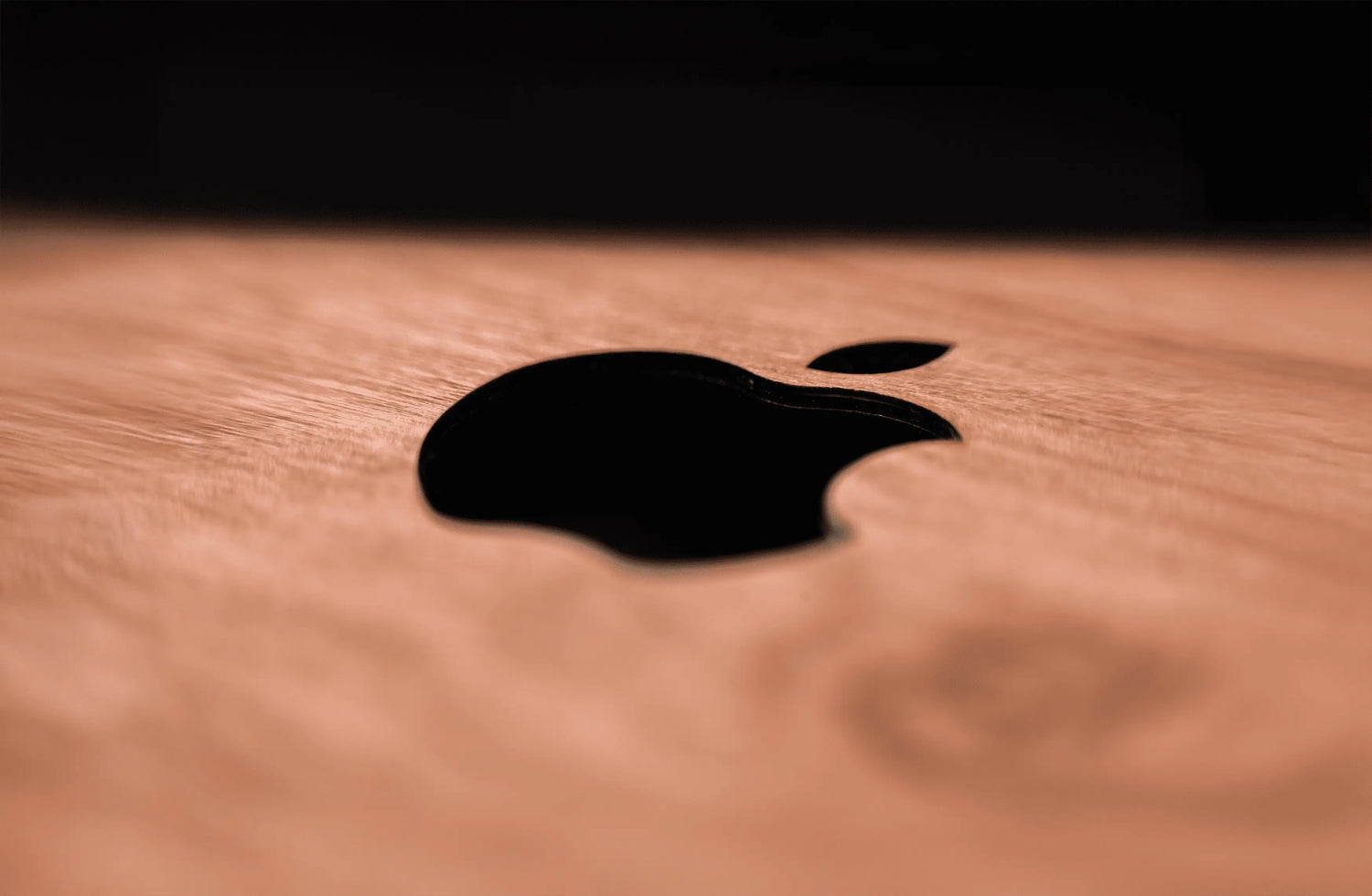 Coque en bois pour ordinateur portable Macbook avec le logo d'Apple photographié de près.