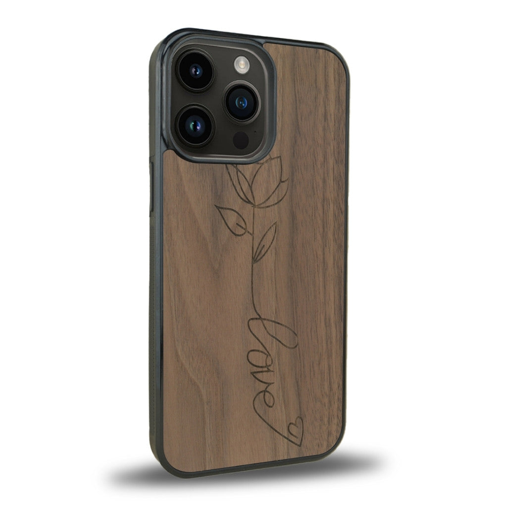 Coque de protection en bois véritable fabriquée en France pour iPhone 13 Pro Max sur le thème de la fête des mères avec un motif représentant une fleur dont la tige forme le mot "love"