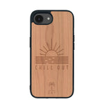 Coque de protection en bois véritable fabriquée en France pour iPhone 16e sur le thème chill avec un motif représentant un couché de soleil sur l'océan et la phrase "Chill out"
