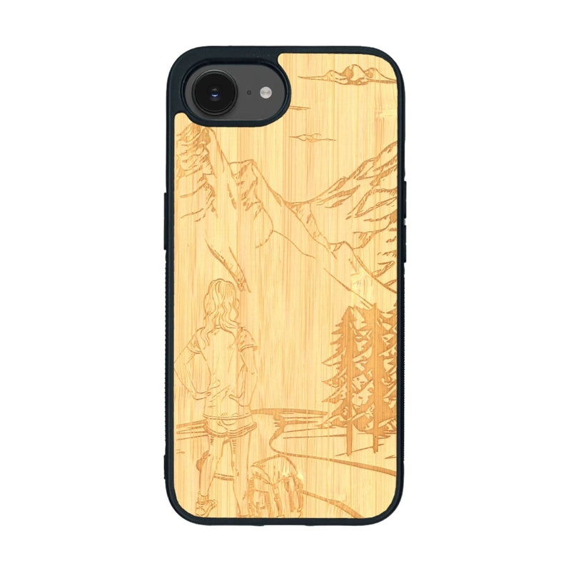 Coque de protection en bois véritable fabriquée en France pour iPhone 16e sur le thème de la randonnée en montagne et de l'aventure avec une gravure représentant une femme de dos face à un paysage de nature