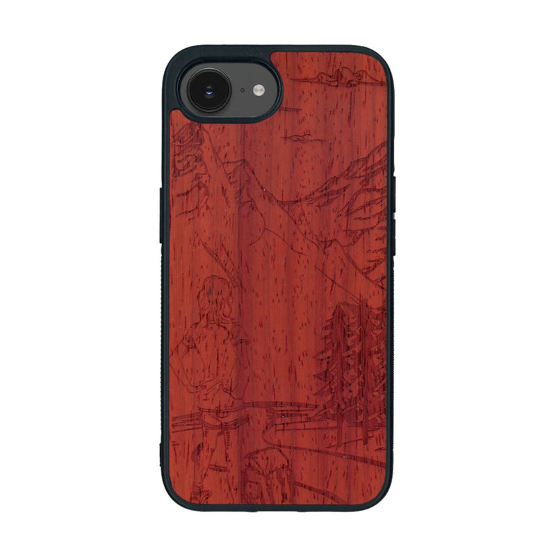 Coque de protection en bois véritable fabriquée en France pour iPhone 16e sur le thème de la randonnée en montagne et de l'aventure avec une gravure représentant une femme de dos face à un paysage de nature