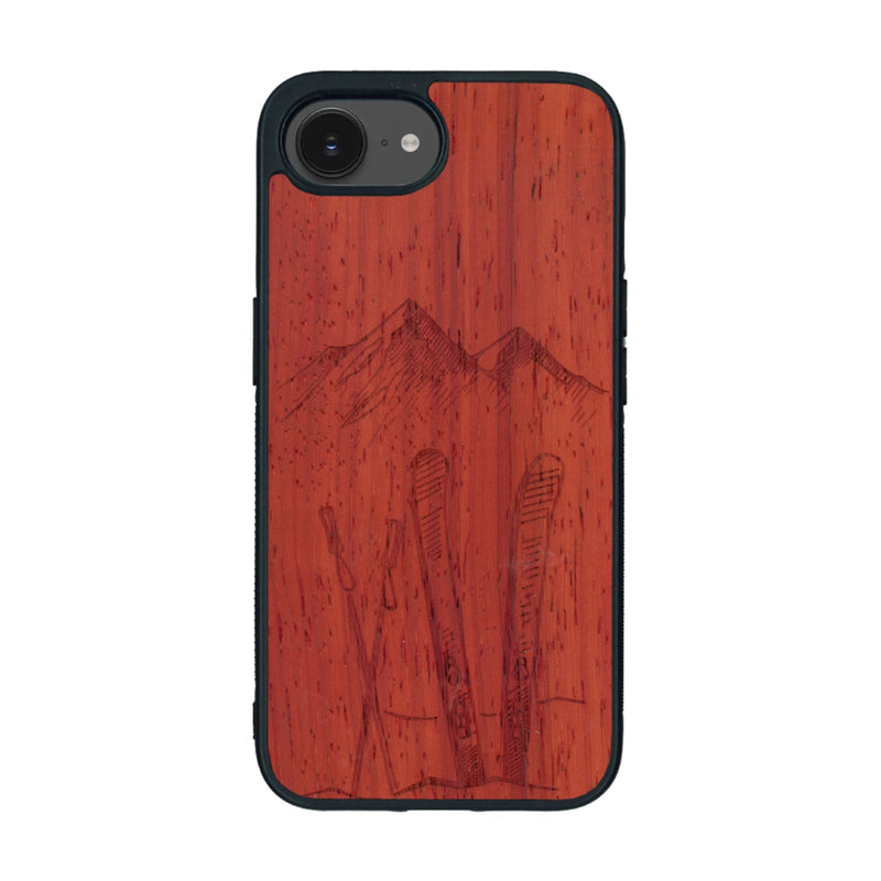 Coque de protection en bois véritable fabriquée en France pour iPhone 16e sur le thème de la montagne, du ski et de la neige avec un motif représentant une paire de ski plantée dans la neige avec en fond des montagnes enneigées