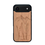 Coque de protection en bois véritable fabriquée en France pour iPhone 17 Air sur le thème de la montagne, du ski et de la neige avec un motif représentant une paire de ski plantée dans la neige avec en fond des montagnes enneigées
