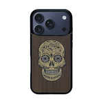 Coque de protection en bois véritable fabriquée en France pour iPhone 17 Pro alliant du chêne fumé avec du métal argenté et doré représentant une tête de mort mexicaine sur le thème Dia de los Muertos