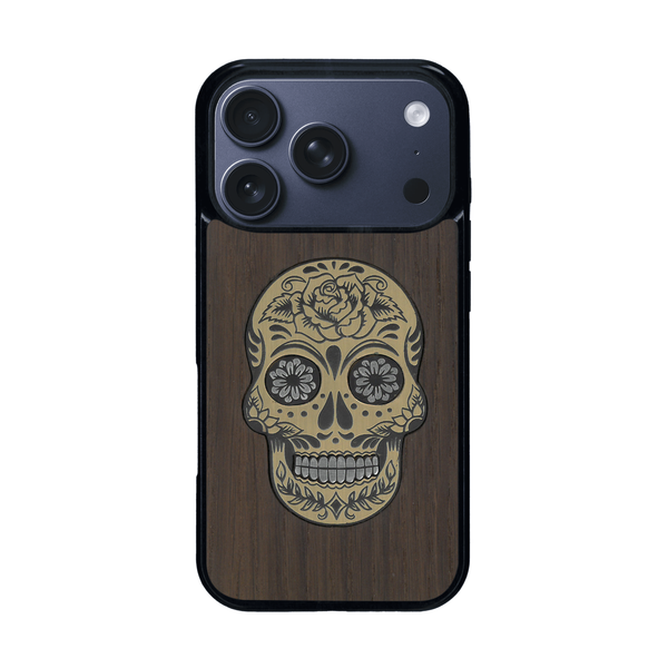 Coque de protection en bois véritable fabriquée en France pour iPhone 17 Pro alliant du chêne fumé avec du métal argenté et doré représentant une tête de mort mexicaine sur le thème Dia de los Muertos