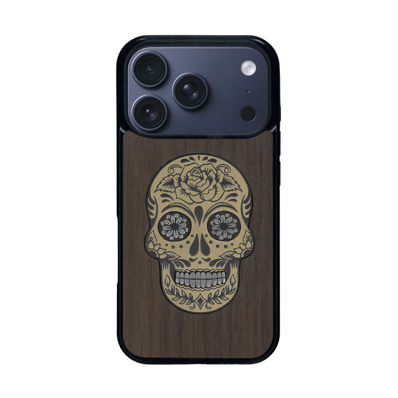 Coque de protection en bois véritable fabriquée en France pour iPhone 17 Pro alliant du chêne fumé avec du métal argenté et doré représentant une tête de mort mexicaine sur le thème Dia de los Muertos