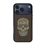 Coque de protection en bois véritable fabriquée en France pour iPhone 17 Pro Max alliant du chêne fumé avec du métal argenté et doré représentant une tête de mort mexicaine sur le thème Dia de los Muertos