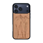 Coque de protection en bois véritable fabriquée en France pour iPhone 17 Pro Max sur le thème de la montagne, du ski et de la neige avec un motif représentant une paire de ski plantée dans la neige avec en fond des montagnes enneigées