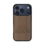 Coque de protection en bois véritable fabriquée en France pour iPhone 17 Pro sur le thème chill et nature avec un motif représentant un levé de soleil sur un paysage de montagne avec des sapins et un chalet et la phrase "Good friends, good adventure"