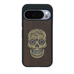 Coque de protection en bois véritable fabriquée en France pour Google Pixel 10 alliant du chêne fumé avec du métal argenté et doré représentant une tête de mort mexicaine sur le thème Dia de los Muertos