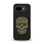 Coque de protection en bois véritable fabriquée en France pour Google Pixel 10A alliant du chêne fumé avec du métal argenté et doré représentant une tête de mort mexicaine sur le thème Dia de los Muertos