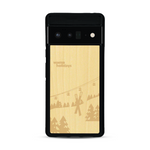 Coque de protection en bois véritable fabriquée en France pour  sur le thème de la montagne, du ski et de la neige avec un motif représentant une paire de ski plantée dans la neige avec en fond des montagnes enneigées