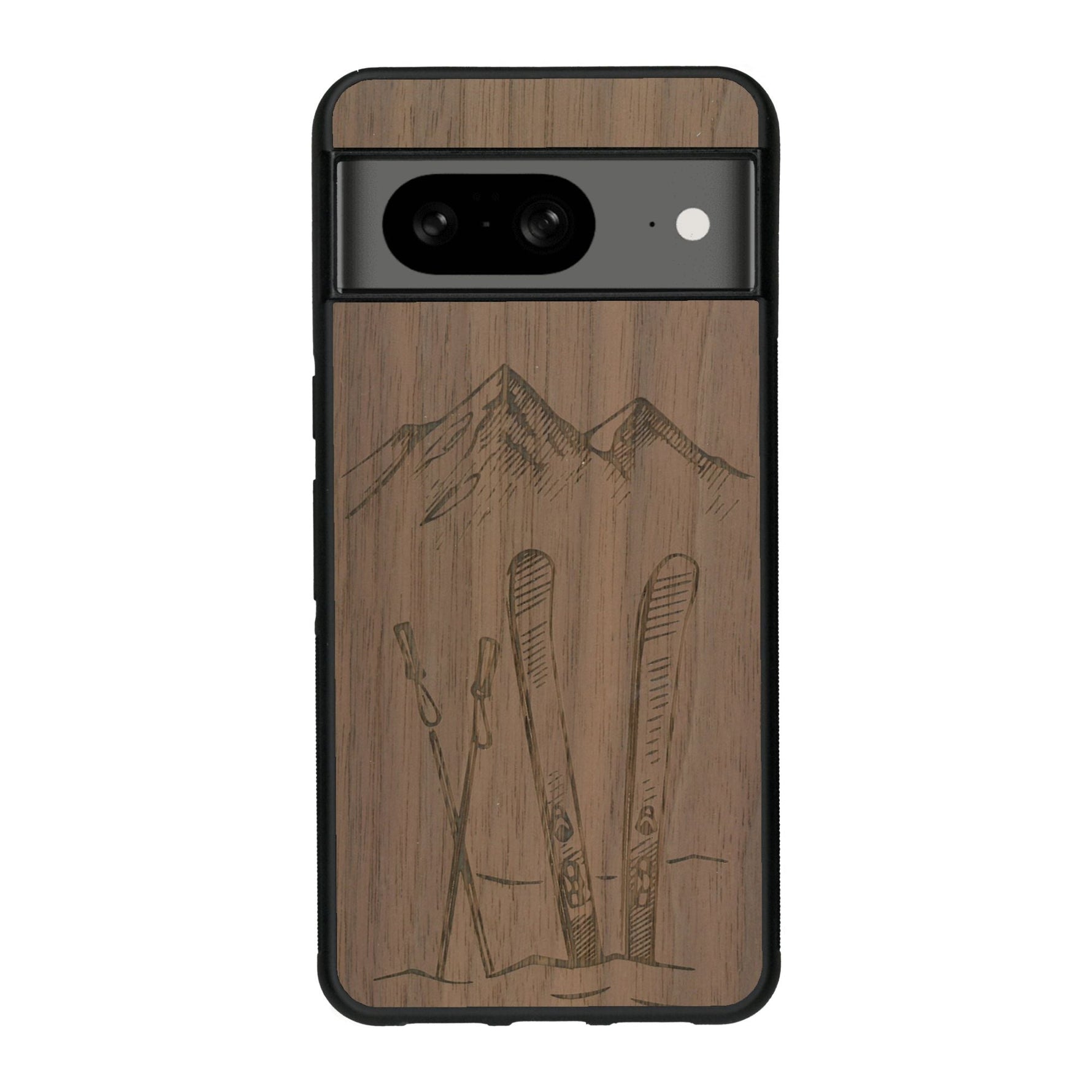 Coque de protection en bois véritable fabriquée en France pour Google Pixel 7A sur le thème de la montagne, du ski et de la neige avec un motif représentant une paire de ski plantée dans la neige avec en fond des montagnes enneigées