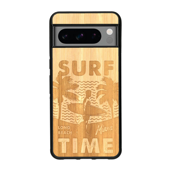 Coque de protection en bois véritable fabriquée en France pour Google Pixel 8pro sur le thème chill avec un motif représentant une silouhette tenant une planche de surf sur une plage entouré de palmiers et les mots "Surf Time Long Beach Miami"