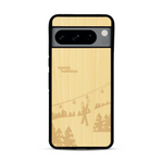 Coque de protection en bois véritable fabriquée en France pour  sur le thème de la montagne, du ski et de la neige avec un motif représentant une paire de ski plantée dans la neige avec en fond des montagnes enneigées
