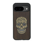 Coque de protection en bois véritable fabriquée en France pour Google Pixel 8pro alliant du chêne fumé avec du métal argenté et doré représentant une tête de mort mexicaine sur le thème Dia de los Muertos