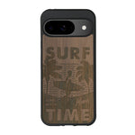 Coque de protection en bois véritable fabriquée en France pour Google Pixel 8A sur le thème chill avec un motif représentant une silouhette tenant une planche de surf sur une plage entouré de palmiers et les mots "Surf Time Long Beach Miami"