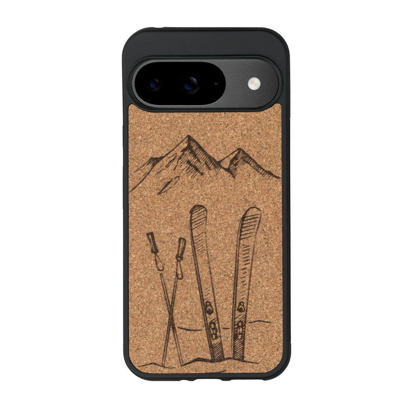 Coque de protection en bois véritable fabriquée en France pour Google Pixel 8A sur le thème de la montagne, du ski et de la neige avec un motif représentant une paire de ski plantée dans la neige avec en fond des montagnes enneigées