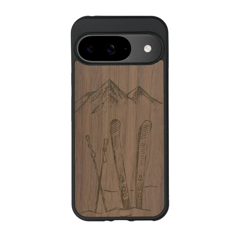 Coque de protection en bois véritable fabriquée en France pour Google Pixel 8A sur le thème de la montagne, du ski et de la neige avec un motif représentant une paire de ski plantée dans la neige avec en fond des montagnes enneigées