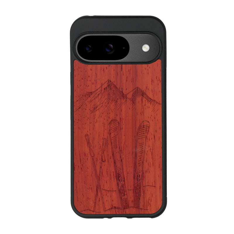 Coque de protection en bois véritable fabriquée en France pour Google Pixel 8A sur le thème de la montagne, du ski et de la neige avec un motif représentant une paire de ski plantée dans la neige avec en fond des montagnes enneigées