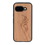 Coque de protection en bois véritable fabriquée en France pour Google Pixel 9A représentant une main de femme tenant une cigarette de type line art en collaboration avec l'artiste Maud Dabs