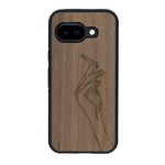 Coque de protection en bois véritable fabriquée en France pour Google Pixel 9A représentant une main de femme tenant une cigarette de type line art en collaboration avec l'artiste Maud Dabs
