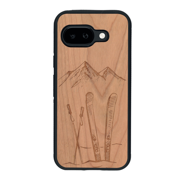 Coque de protection en bois véritable fabriquée en France pour Google Pixel 9A sur le thème de la montagne, du ski et de la neige avec un motif représentant une paire de ski plantée dans la neige avec en fond des montagnes enneigées