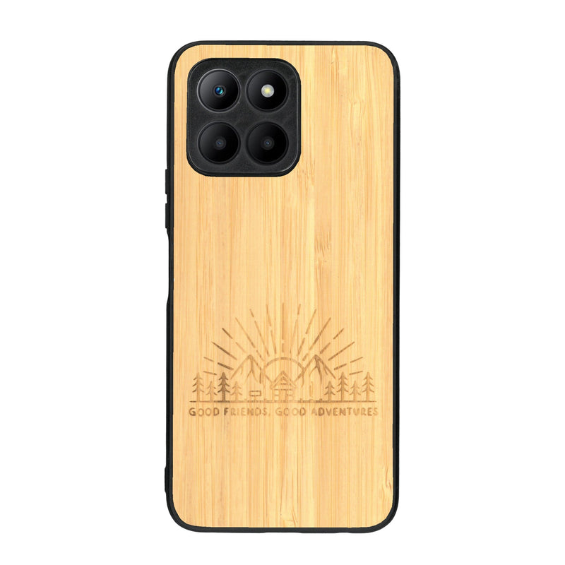 Coque de protection en bois véritable fabriquée en France pour Honor 70 Lite sur le thème chill et nature avec un motif représentant un levé de soleil sur un paysage de montagne avec des sapins et un chalet et la phrase "Good friends, good adventure"