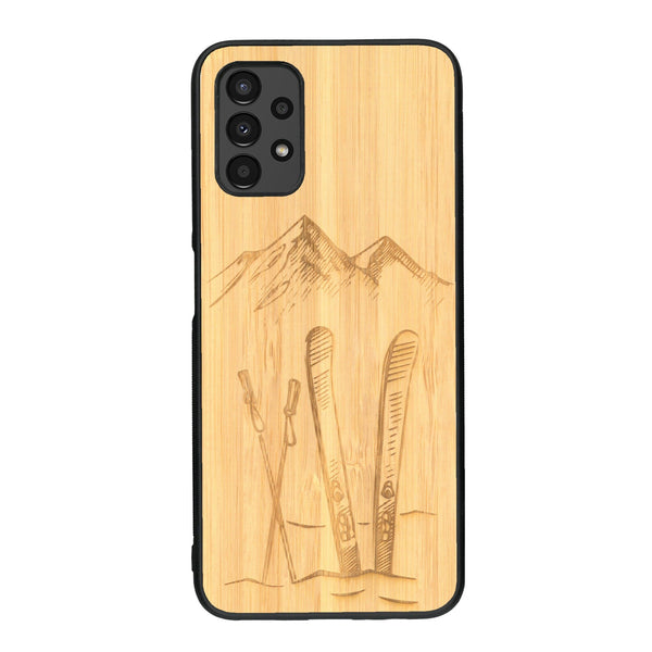 Coque de protection en bois véritable fabriquée en France pour Samsung A13 sur le thème de la montagne, du ski et de la neige avec un motif représentant une paire de ski plantée dans la neige avec en fond des montagnes enneigées