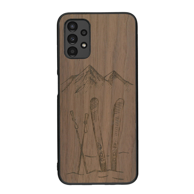 Coque de protection en bois véritable fabriquée en France pour Samsung A13 sur le thème de la montagne, du ski et de la neige avec un motif représentant une paire de ski plantée dans la neige avec en fond des montagnes enneigées