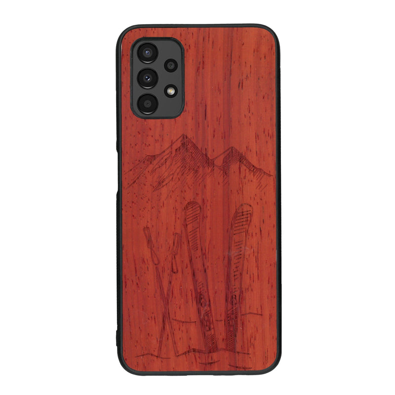 Coque de protection en bois véritable fabriquée en France pour Samsung A13 sur le thème de la montagne, du ski et de la neige avec un motif représentant une paire de ski plantée dans la neige avec en fond des montagnes enneigées