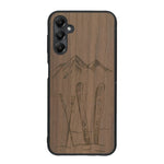 Coque de protection en bois véritable fabriquée en France pour Samsung A15 sur le thème de la montagne, du ski et de la neige avec un motif représentant une paire de ski plantée dans la neige avec en fond des montagnes enneigées