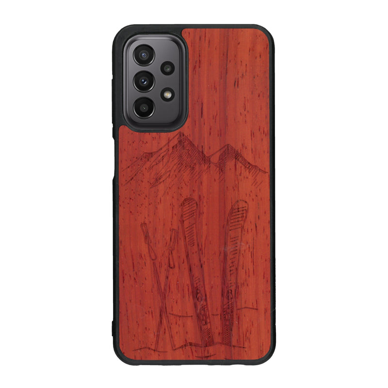 Coque de protection en bois véritable fabriquée en France pour Samsung A23 sur le thème de la montagne, du ski et de la neige avec un motif représentant une paire de ski plantée dans la neige avec en fond des montagnes enneigées