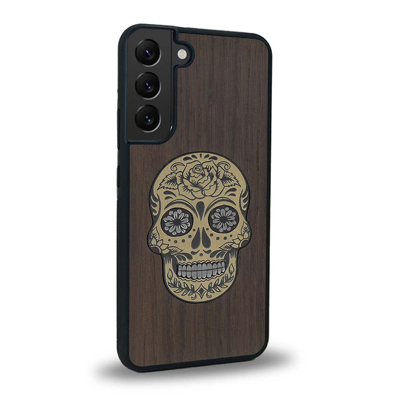 Coque de protection en bois véritable fabriquée en France pour Samsung S24 alliant du chêne fumé avec du métal argenté et doré représentant une tête de mort mexicaine sur le thème Dia de los Muertos