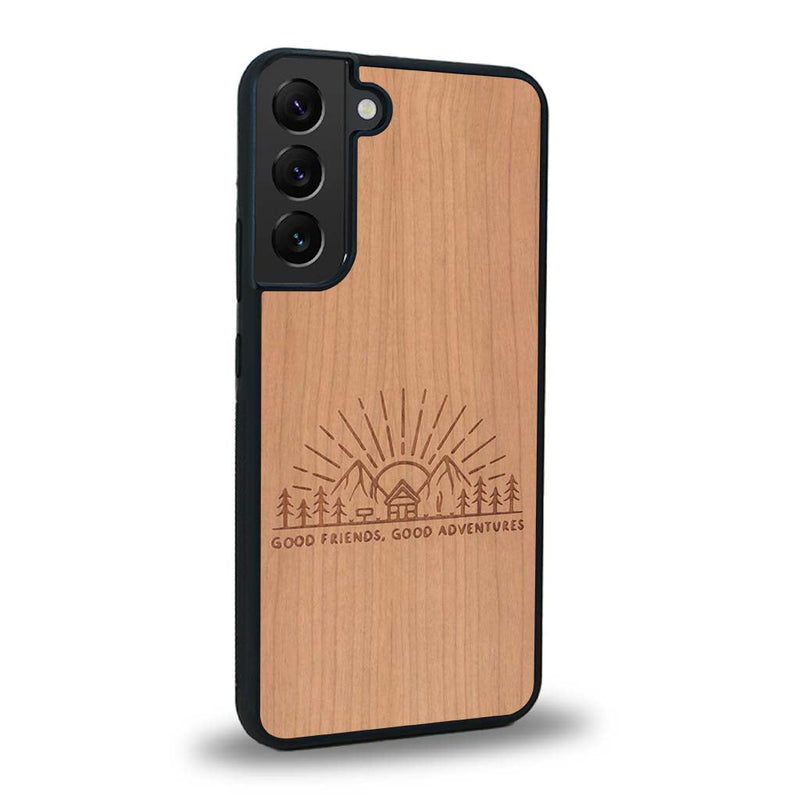 Coque de protection en bois véritable fabriquée en France pour Samsung S24 sur le thème chill et nature avec un motif représentant un levé de soleil sur un paysage de montagne avec des sapins et un chalet et la phrase "Good friends, good adventure"