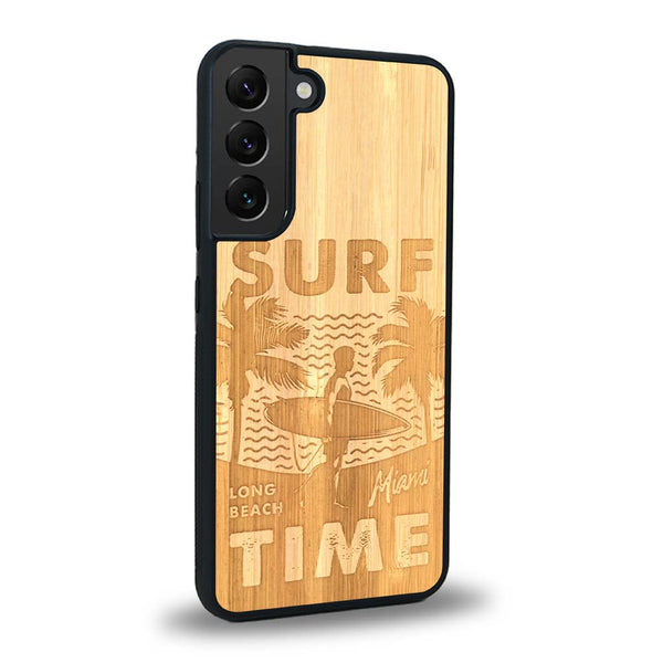 Coque de protection en bois véritable fabriquée en France pour Samsung S24 sur le thème chill avec un motif représentant une silouhette tenant une planche de surf sur une plage entouré de palmiers et les mots "Surf Time Long Beach Miami"