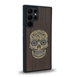 Coque de protection en bois véritable fabriquée en France pour Samsung S24 Ultra alliant du chêne fumé avec du métal argenté et doré représentant une tête de mort mexicaine sur le thème Dia de los Muertos