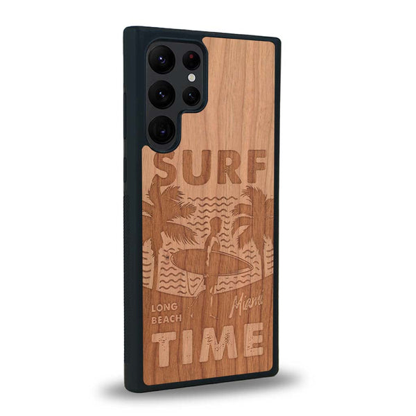 Coque de protection en bois véritable fabriquée en France pour Samsung S24 Ultra sur le thème chill avec un motif représentant une silouhette tenant une planche de surf sur une plage entouré de palmiers et les mots "Surf Time Long Beach Miami"