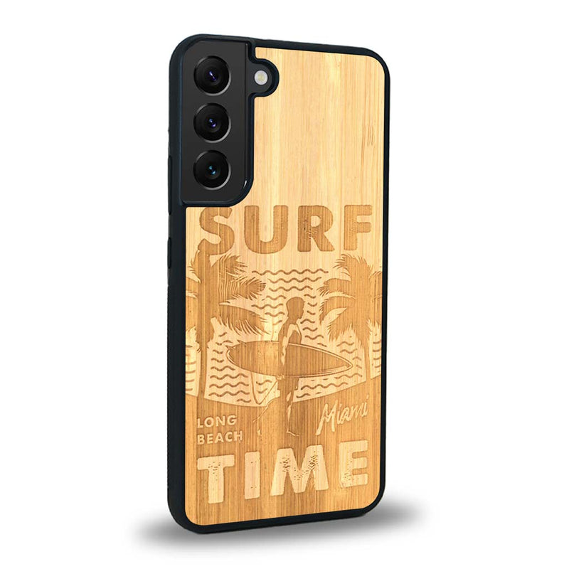 Coque de protection en bois véritable fabriquée en France pour Samsung S24FE sur le thème chill avec un motif représentant une silouhette tenant une planche de surf sur une plage entouré de palmiers et les mots "Surf Time Long Beach Miami"