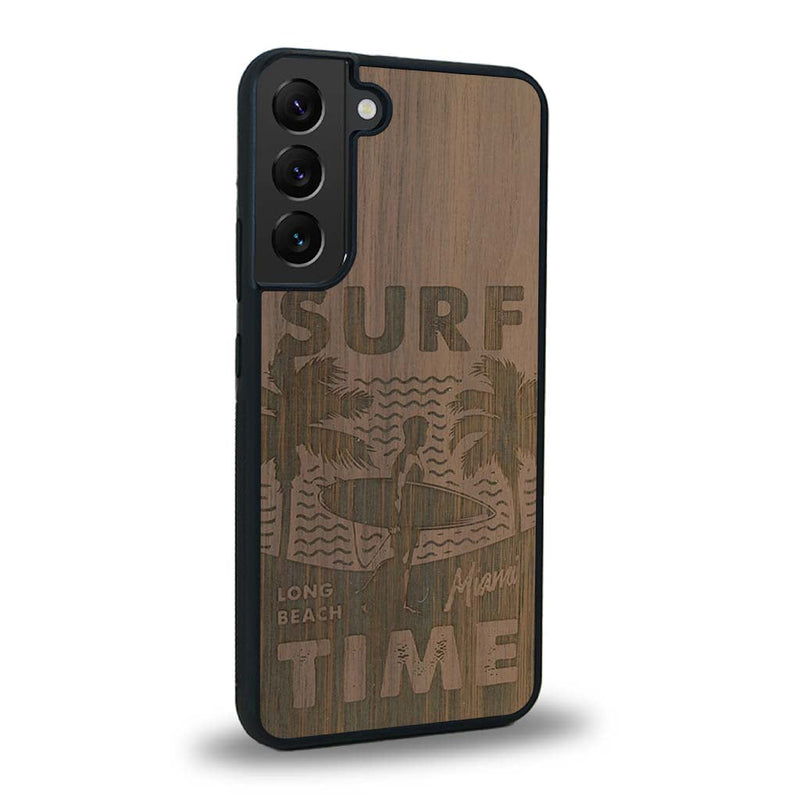 Coque de protection en bois véritable fabriquée en France pour Samsung S24+ sur le thème chill avec un motif représentant une silouhette tenant une planche de surf sur une plage entouré de palmiers et les mots "Surf Time Long Beach Miami"