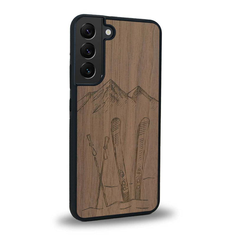 Coque de protection en bois véritable fabriquée en France pour Samsung S24+ sur le thème de la montagne, du ski et de la neige avec un motif représentant une paire de ski plantée dans la neige avec en fond des montagnes enneigées