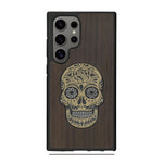 Coque de protection en bois véritable fabriquée en France pour Samsung S25 Ultra alliant du chêne fumé avec du métal argenté et doré représentant une tête de mort mexicaine sur le thème Dia de los Muertos