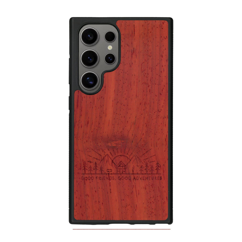 Coque de protection en bois véritable fabriquée en France pour Samsung S25 Ultra sur le thème chill et nature avec un motif représentant un levé de soleil sur un paysage de montagne avec des sapins et un chalet et la phrase "Good friends, good adventure"