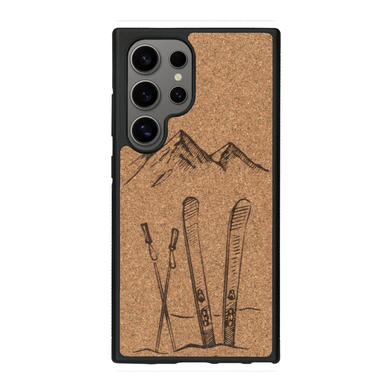 Coque de protection en bois véritable fabriquée en France pour Samsung S25 Ultra sur le thème de la montagne, du ski et de la neige avec un motif représentant une paire de ski plantée dans la neige avec en fond des montagnes enneigées