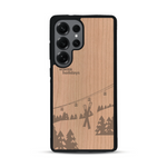 Coque de protection en bois véritable fabriquée en France pour  sur le thème de la montagne, du ski et de la neige avec un motif représentant une paire de ski plantée dans la neige avec en fond des montagnes enneigées